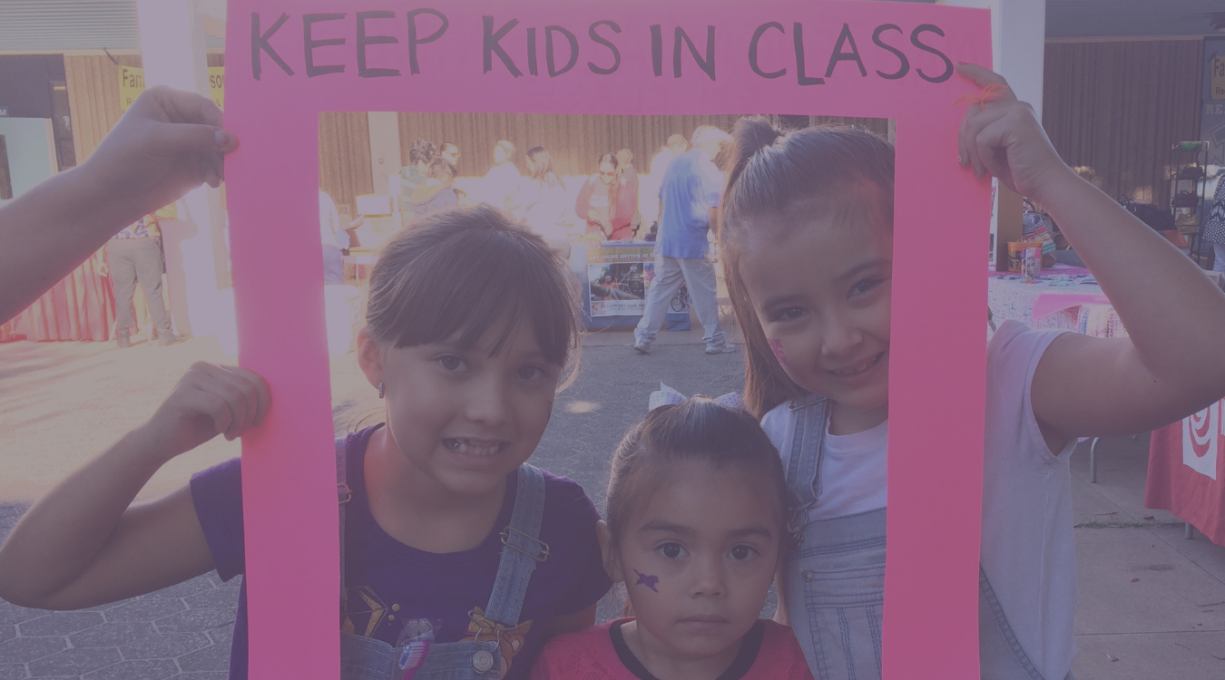 2016 Hope Fest event, three young schoolgirls hold a picture frame about the need to keep kids in class