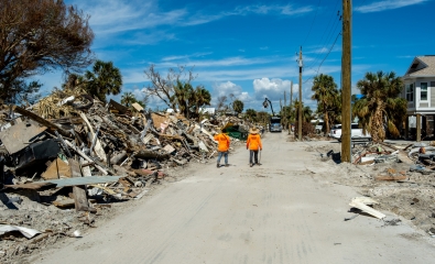 Fort Myers Beach, Florida - October 26, 2022: Workers walking along piles of debris near Estero Blvd