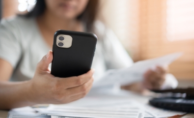 Worried woman looking at phone and paying bills stock photo