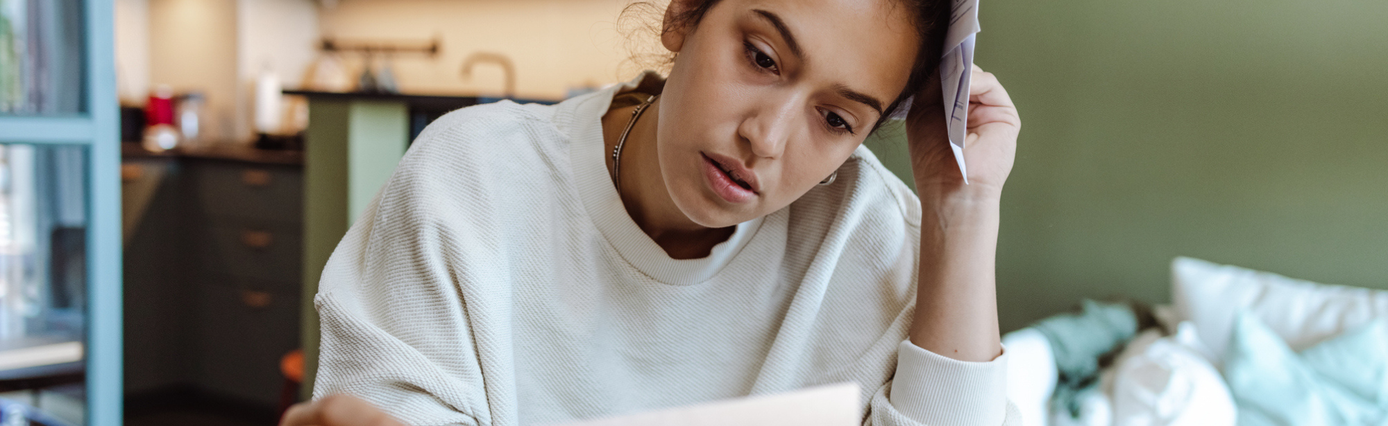 Worried woman holding expense bills against her head