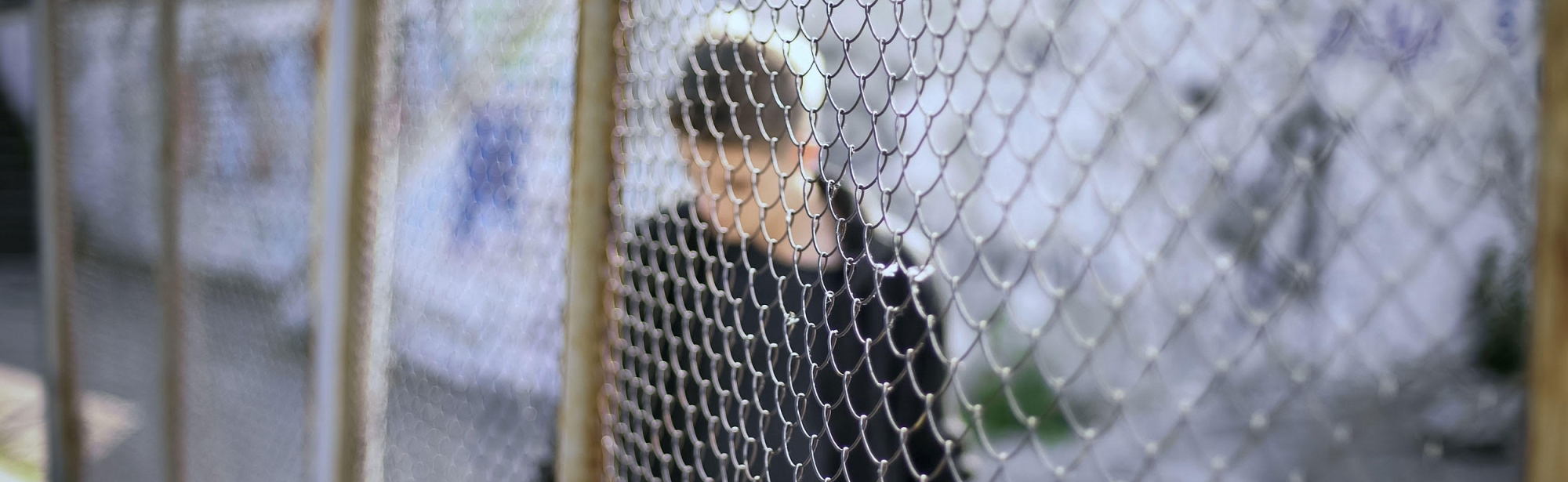 Boy stands by fence